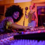 Mezcladora de sonido en estudio de grabación, artista africana disfrutando de su creatividad musical en un entorno profesional.
