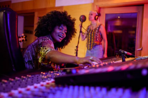 Mezcladora de sonido en estudio de grabación, artista africana disfrutando de su creatividad musical en un entorno profesional.